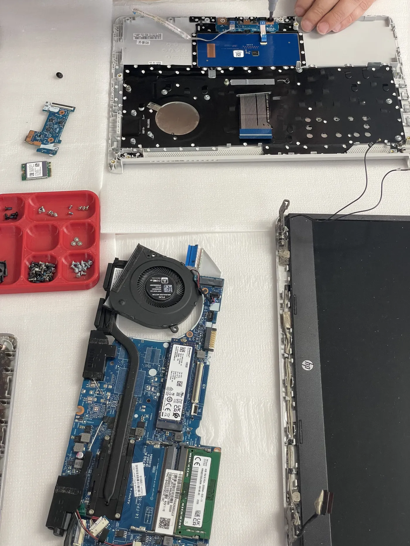 Carte mère, ventilateur et écran d’un HP démonté sur le plan de travail de l’atelier Greenleo